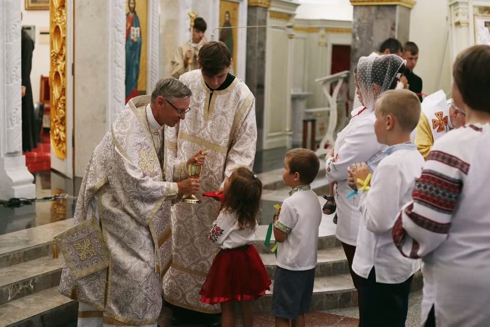 Bishop David offers holy communion to children during Divine Liturgy in church.