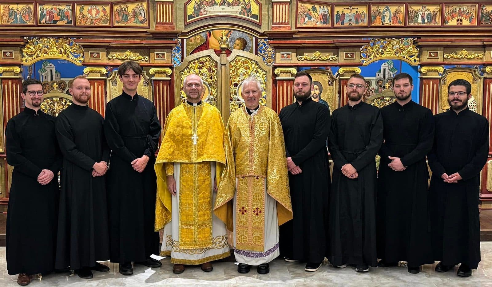 Seminarians and clergy gather before an ornate iconostasis in prayerful community