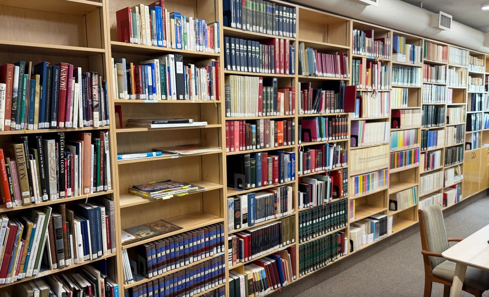 Shelves in a church library hold religious, theological, and reference books in a quiet reading room.