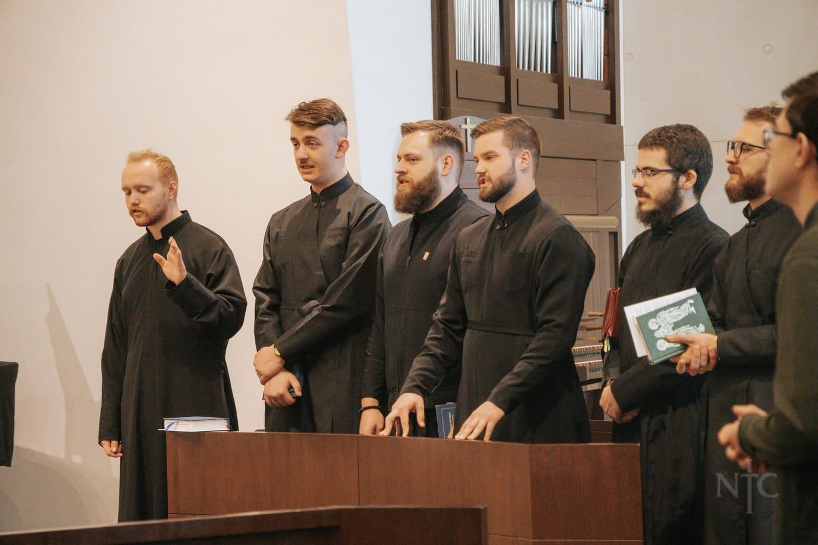 Men in black clerical vestments gathered inside a church during seminary formation.