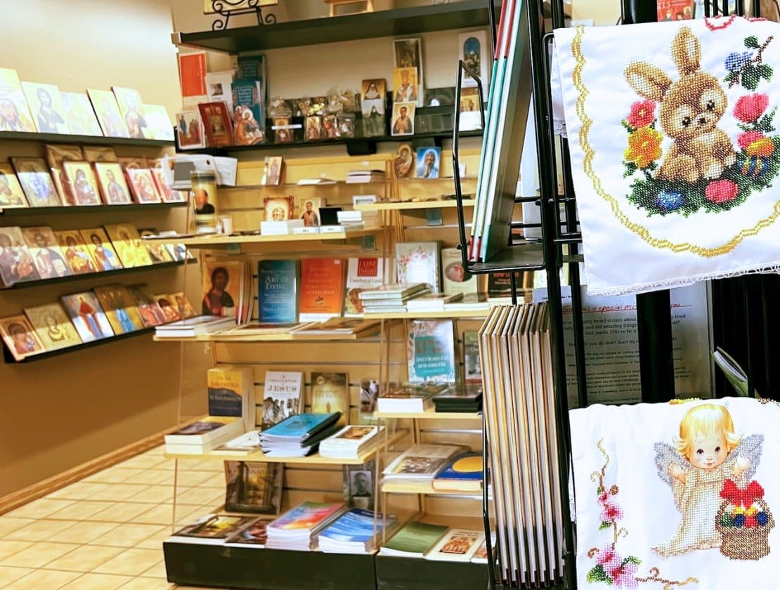 Shelves in a church store display Byzantine icons, religious books, and faith gifts.