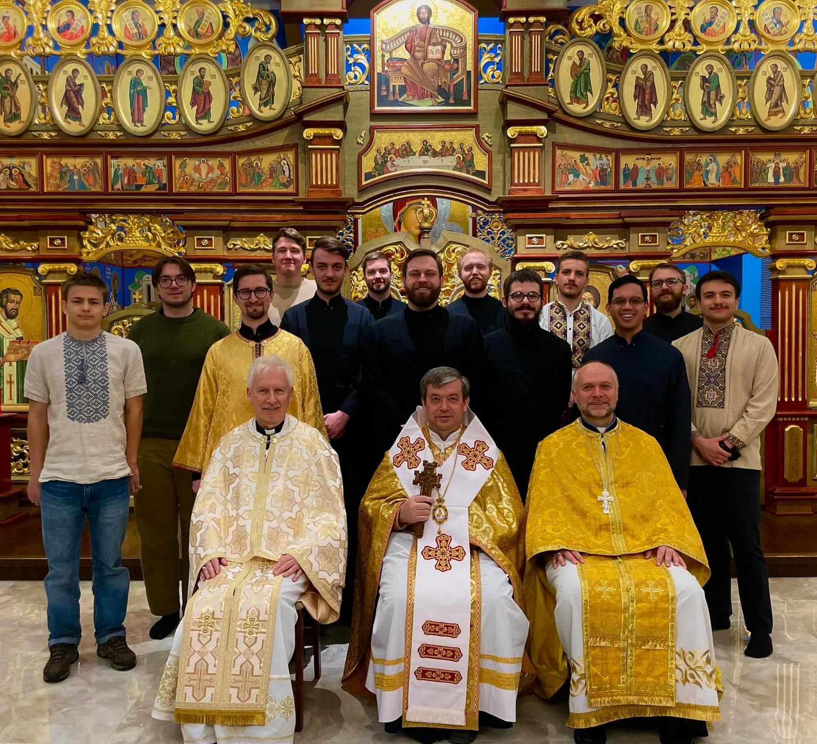Clergy and laymen pose in front of a richly decorated iconostasis.