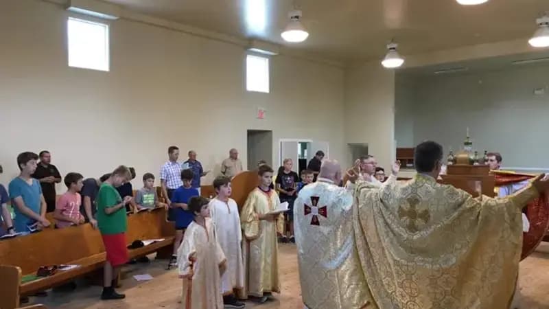 Priests in ornate vestments lead a children's choir during a Divine Liturgy.